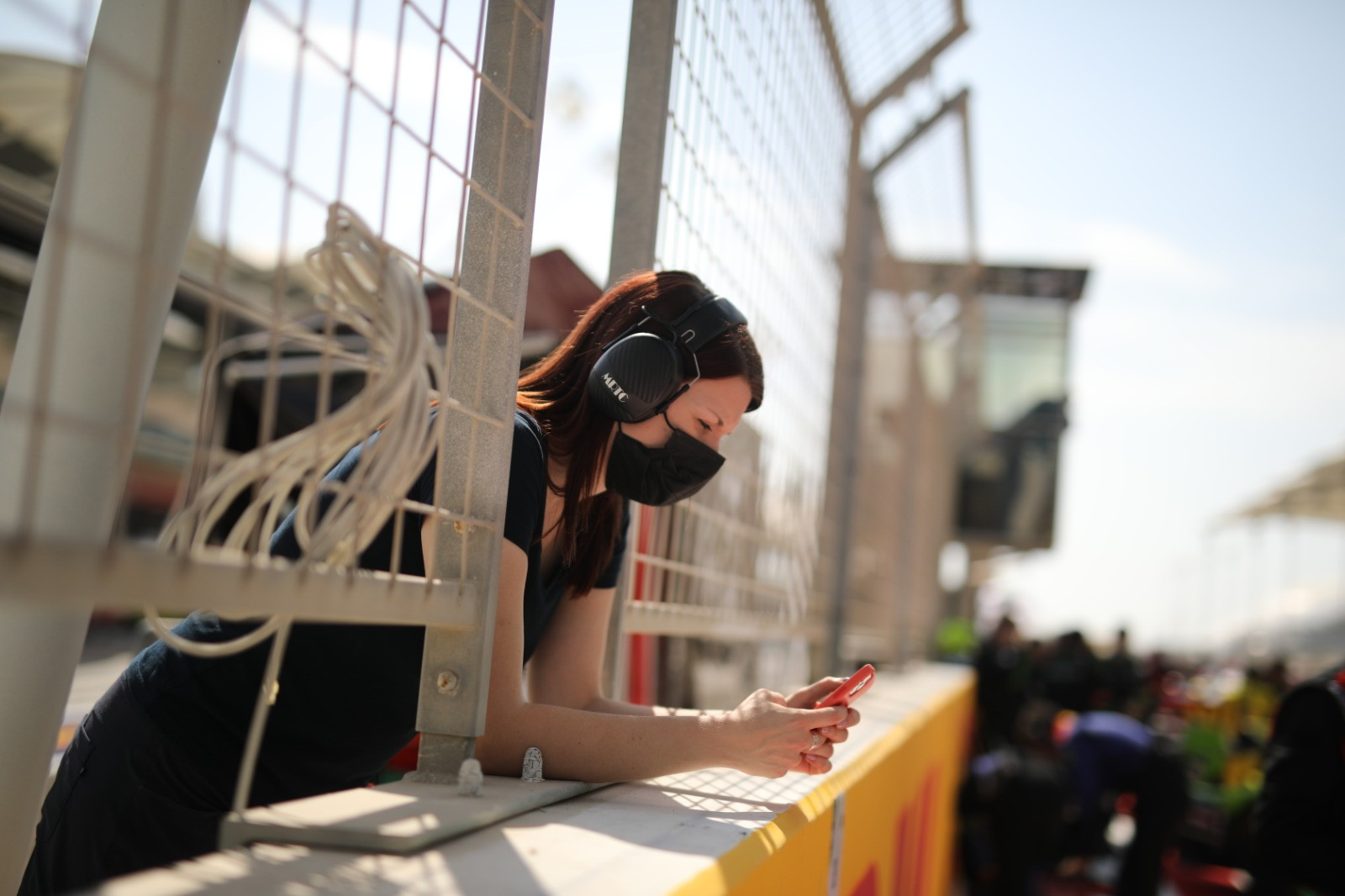 PR person leaning over the pit wall on their phone
