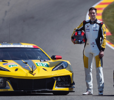 Racing Driver Oliver Gavin standing next to yellow corvette racing car holding his helmet